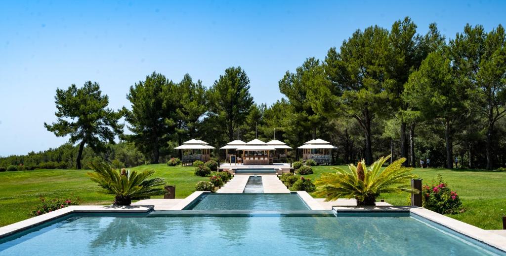 a swimming pool in the middle of a yard with trees at L'Hôtel & Spa du Castellet in Le Castellet
