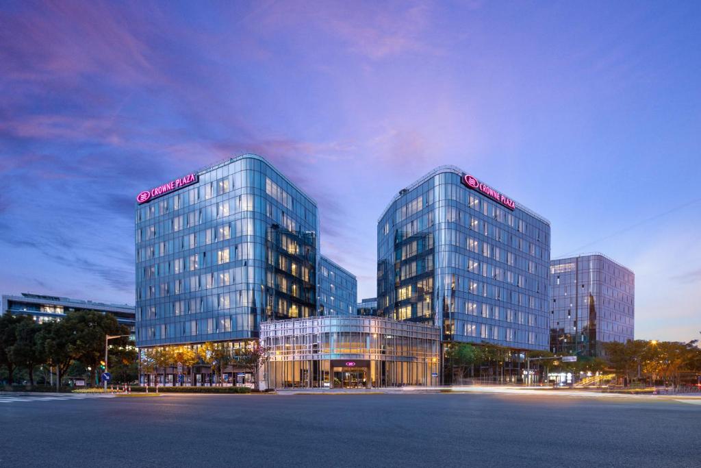 deux grands bâtiments en verre dans une ville la nuit dans l'établissement Crowne Plaza Shanghai Hongqiao, an IHG Hotel, à Shanghai