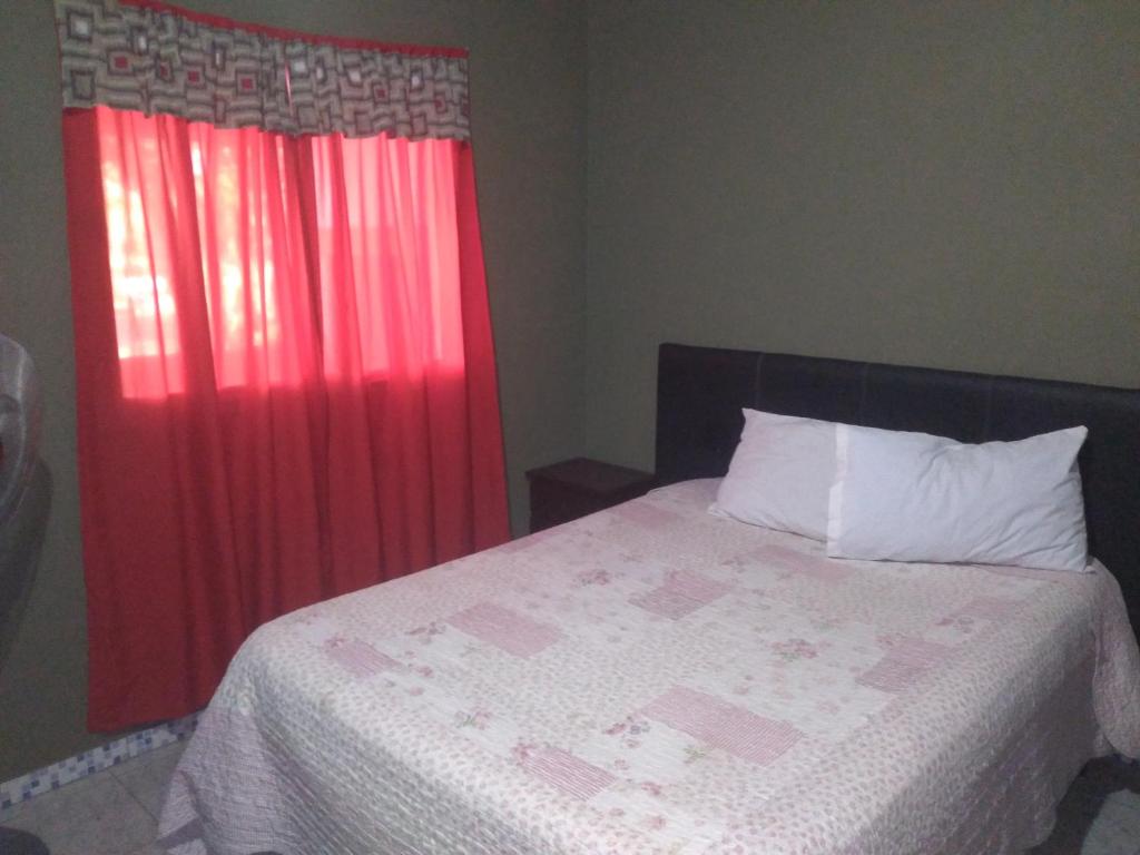 a bedroom with a bed with a red curtain at Susurro de Montaña (TIERRA SANTA) in San Lorenzo