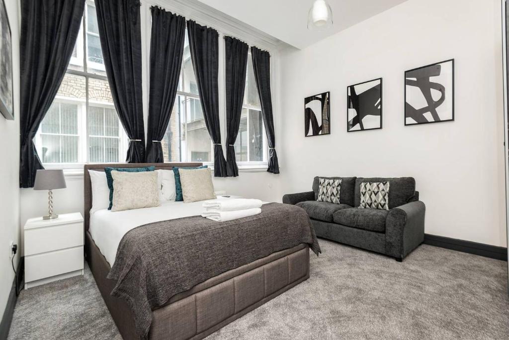 um quarto com uma cama, um sofá e janelas em Host & Stay - Exchange Quarters em Liverpool