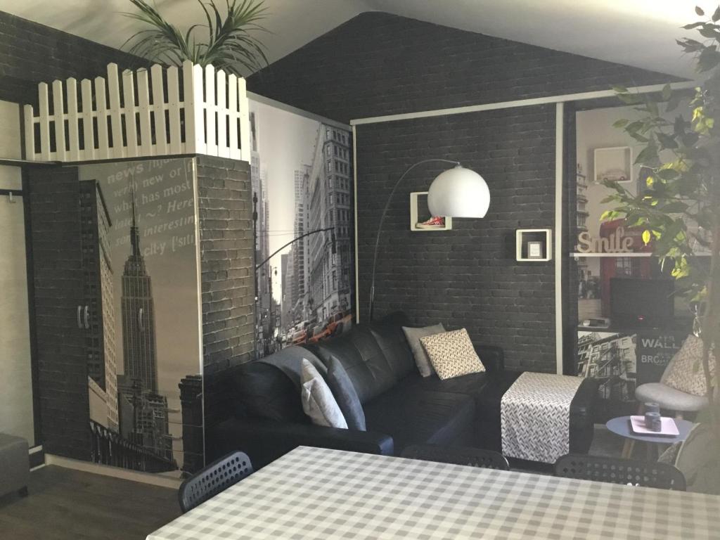 ein Wohnzimmer mit einem schwarzen Sofa und einem Tisch in der Unterkunft Résidence de la plage in Trouville-sur-Mer