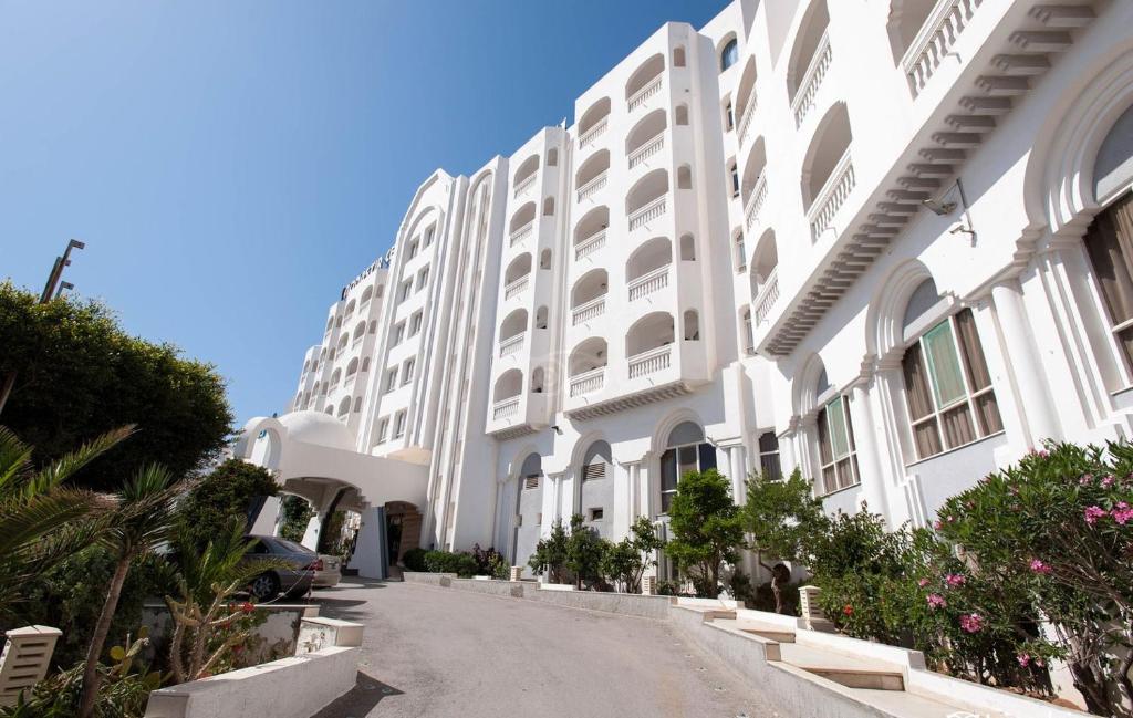 un gran edificio blanco con un coche estacionado al lado en City Business Monastir Center, en Monastir