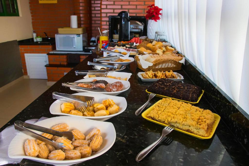 un buffet con muchos platos de comida en una barra en Pousada Rosália, en Penha