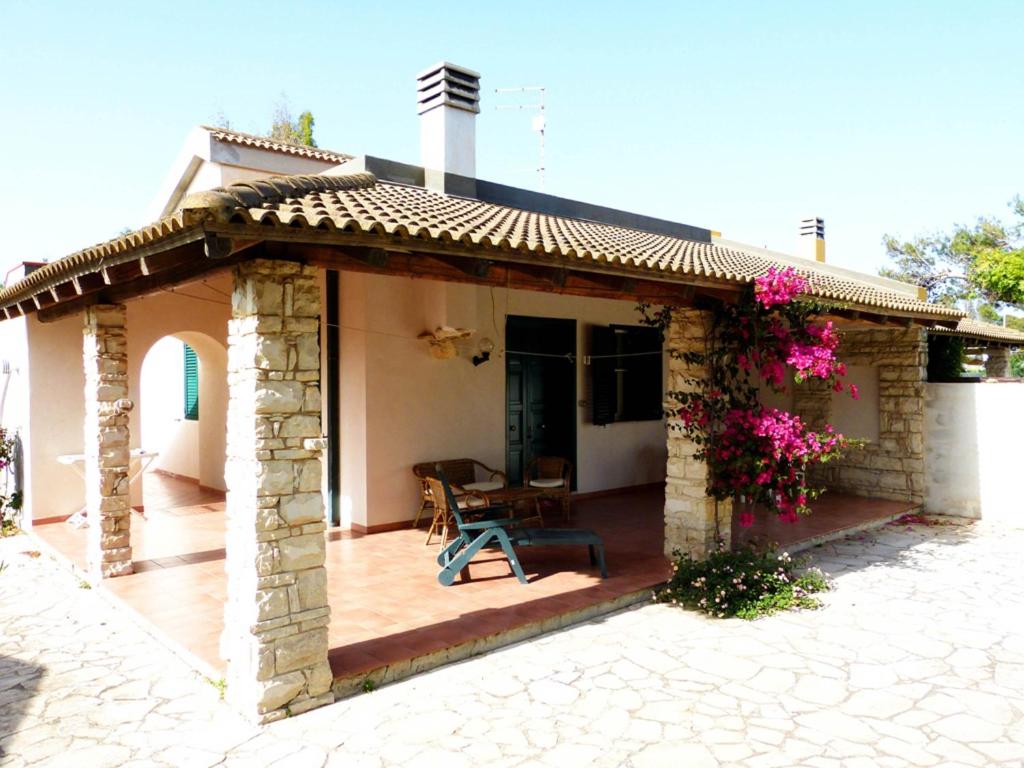 a house with a pavilion with a table and flowers at Casa Vacanza Ondablu CaseSicule, on the Beach with big Veranda and Wifi in Santa Maria Del Focallo