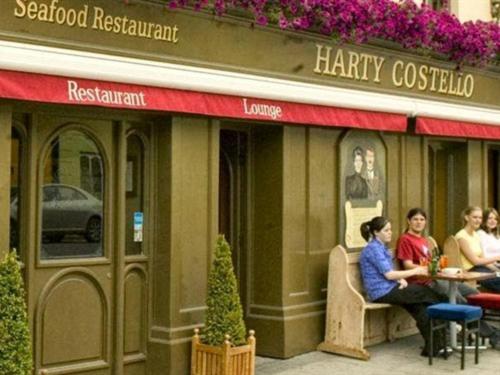 巴利布尼恩的住宿－Harty Costello Town House，一群人坐在餐厅外的桌子上