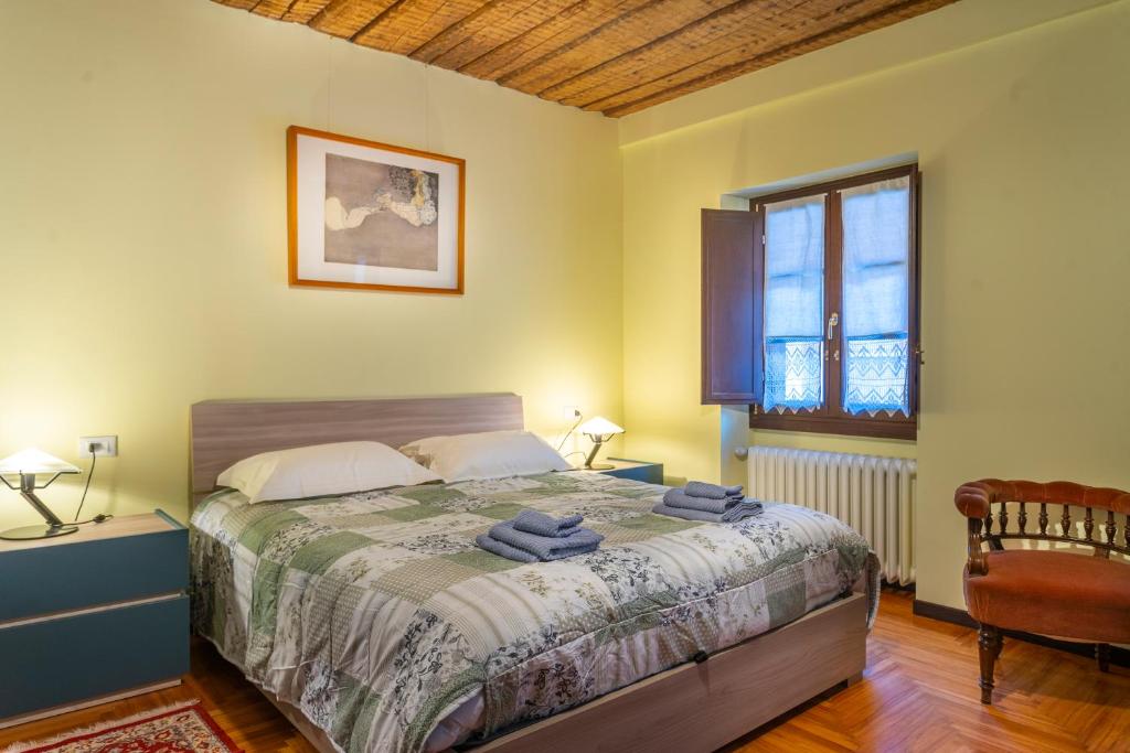a bedroom with a bed and a chair and a window at Hladik House - Alpi Giulie Cosy Apartment in Tarvisio