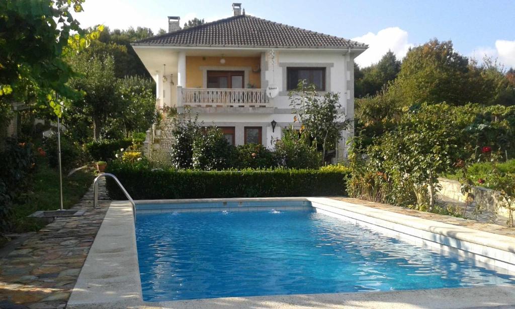 a house with a swimming pool in front of a house at Villa con piscina en Pantòn Ribeira Sacra Galicia Ideal para familias in Follés