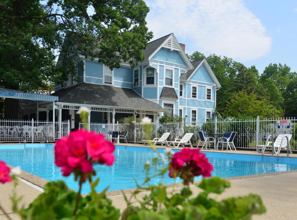 a blue house with a swimming pool and pink flowers at White Rose Inns & Motel in Wisconsin Dells