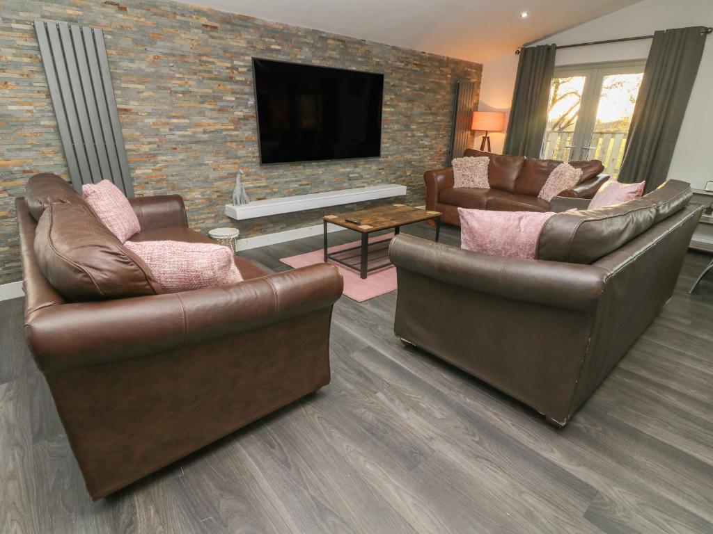 a living room with brown leather furniture and a tv at Box Tree Escapes in Lancaster