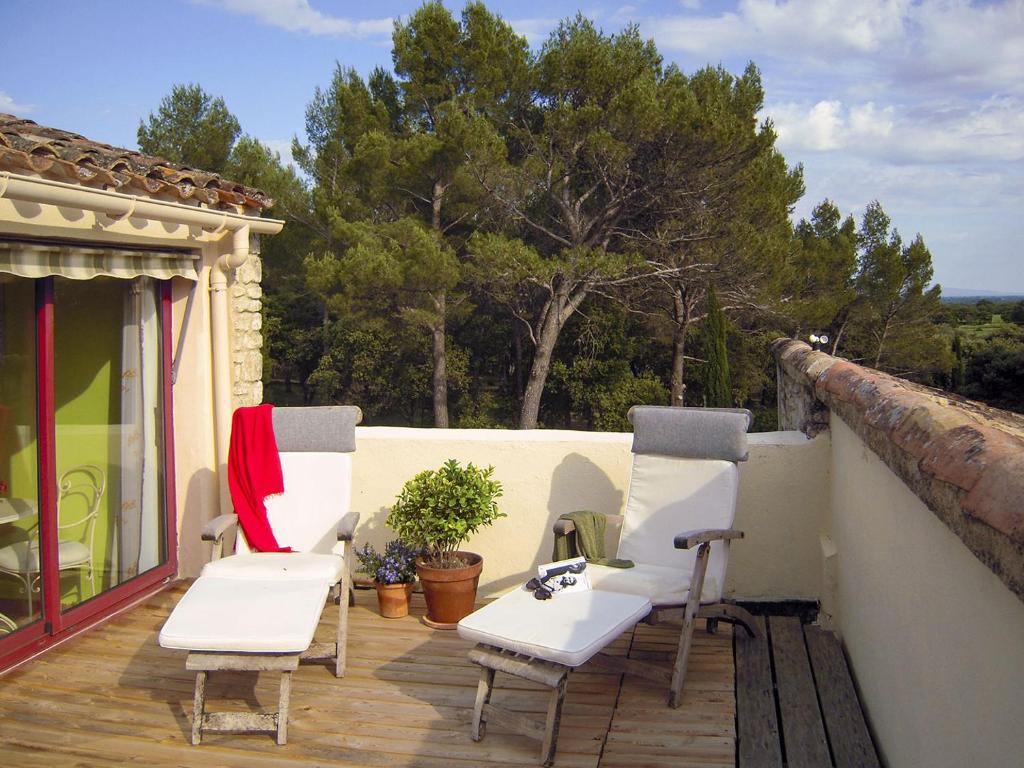 a patio with white chairs on a wooden deck at Le Clos des Chênes in Lagarde-Paréol