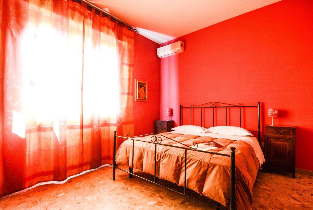 セニガッリアにあるB&B Casa Fuori Casa 200 mt dal casello autostradaleのベッドルーム1室(赤い壁のベッド1台、窓付)