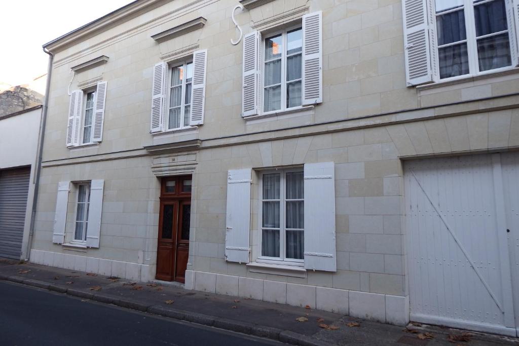 un edificio con ventanas blancas y una puerta en una calle en Chez Florence et Sylvain de Loudun, en Loudun