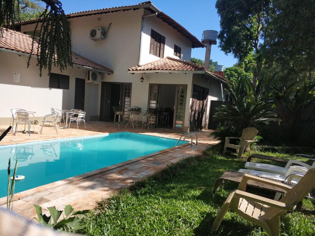 uma villa com piscina em frente a uma casa em Pousada Falls Park em Foz do Iguaçu