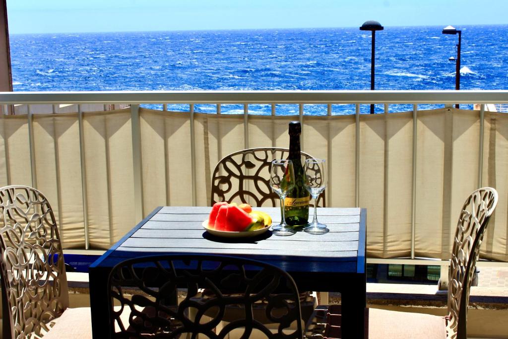 uma mesa com uma garrafa de vinho e um prato de melancia em 2BDR Ocean view apartment em Poris de Abona