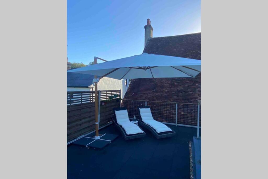 een patio met 2 stoelen en een parasol bij Overton Annexe in Basingstoke