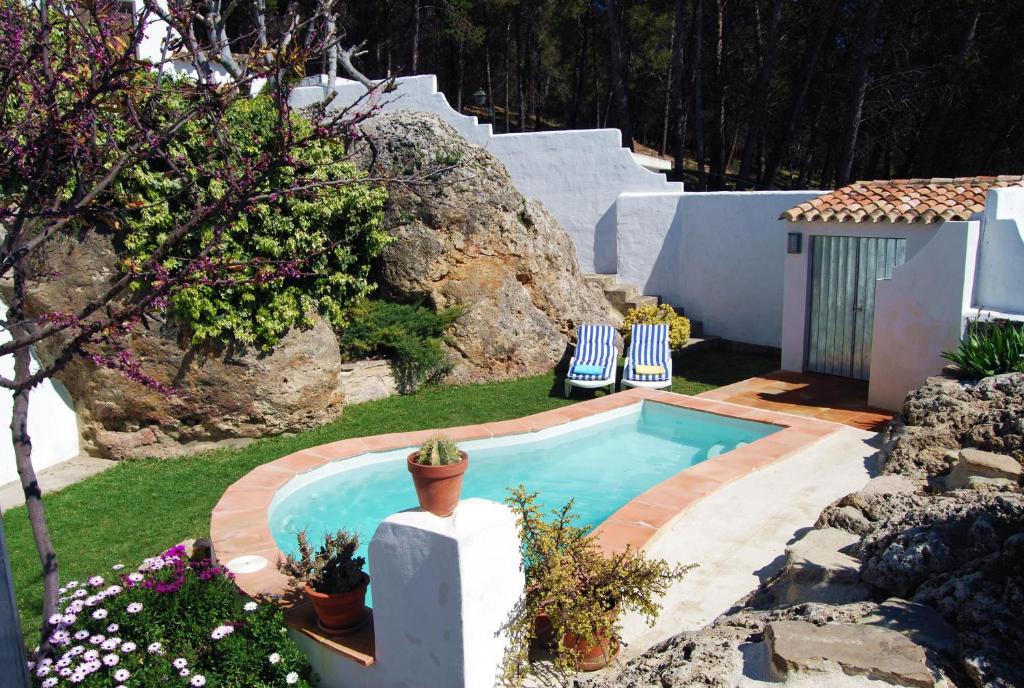 une piscine avec deux chaises et une maison dans l'établissement Villa La Roca - A fusion of modern and typical Andalucian architecture, à Montecorto