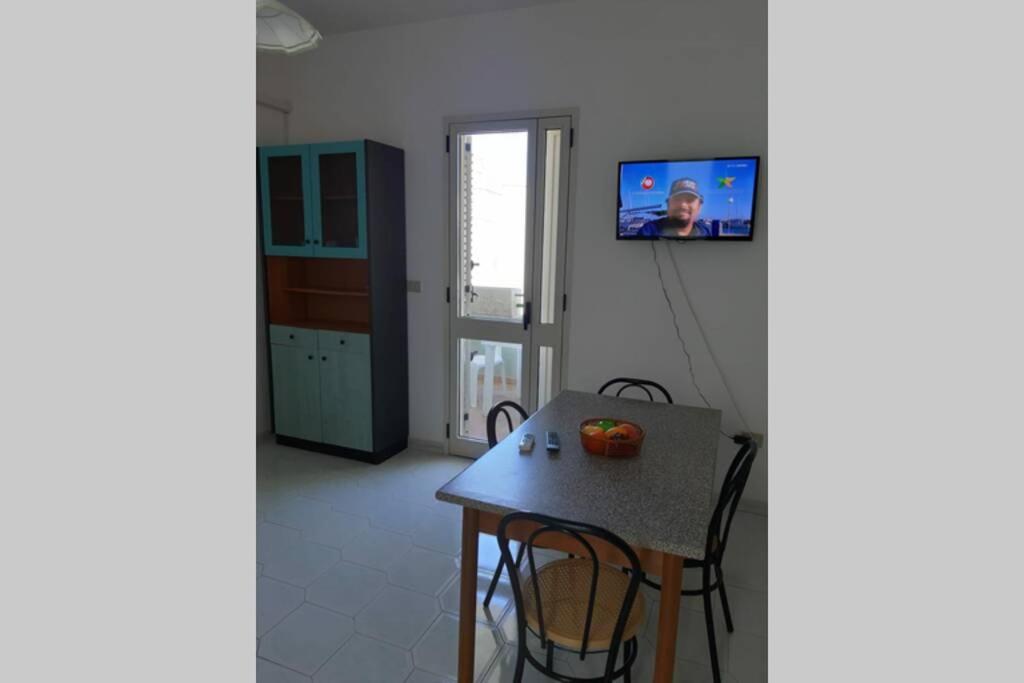 une cuisine avec une table et une télévision murale dans l'établissement Casa Vacanze Iris (Baia Verde), à Baia Verde