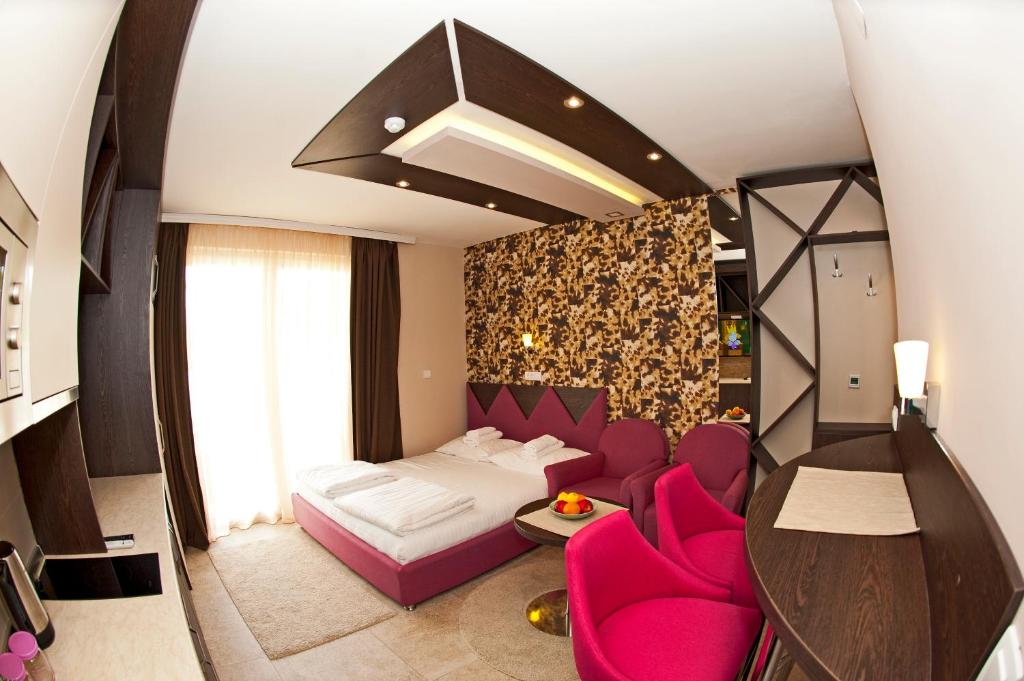 Habitación de hotel con cama y sillas rosas en Apartman NERA - u Kraljevim čardacima Kopaonik, en Kopaonik