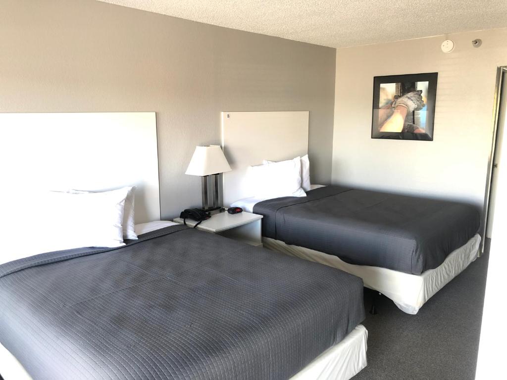 a hotel room with two beds and a lamp at BestWay Inn Oklahoma City Airport in Oklahoma City