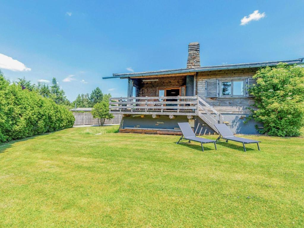 a house with two chairs sitting in the yard at Traditional chalet with garden near Malmedy in Malmedy