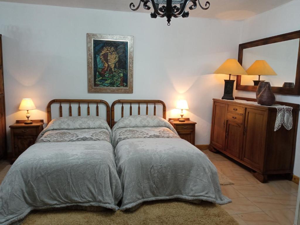 a bedroom with a bed and two lamps and a mirror at Casa MiraXurés con vistas a la Sierra del Xurés in Ourense
