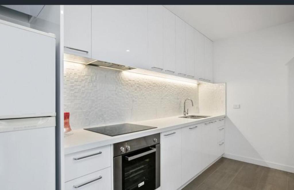 a white kitchen with a sink and a stove at Luxury Beach Front Appartment in Rosebud