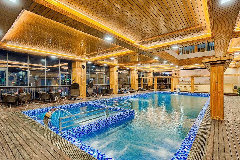 An indoor swimming pool with a tiled spa section and surrounding deck.