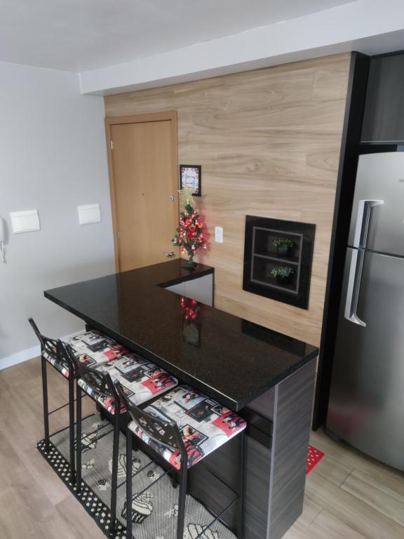 a kitchen with a black counter and a refrigerator at Apartamento no Residencial Vert em Bento Gonçalves-RS in Bento Gonçalves