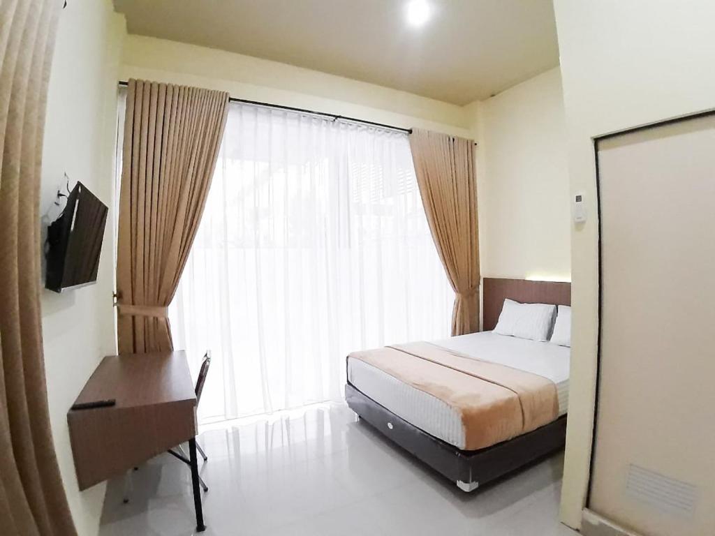 a bedroom with a bed and a large window at RedDoorz Syariah near Transmart Jambi 2 in Paalmerah