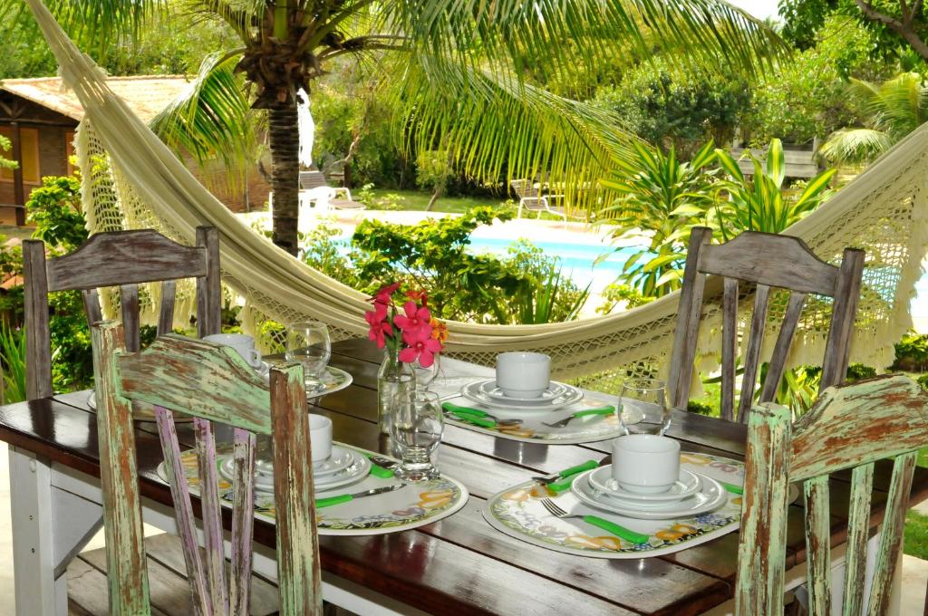 a table with chairs and a hammock and a pool at Refúgio do Corsário-Imbassai-Ba in Imbassai