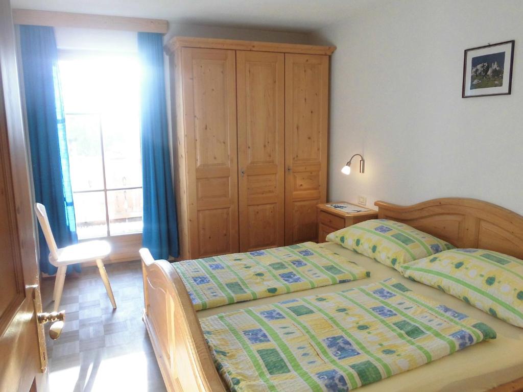 sypialnia z łóżkiem, krzesłem i oknem w obiekcie Villa Bernhard w mieście Siusi