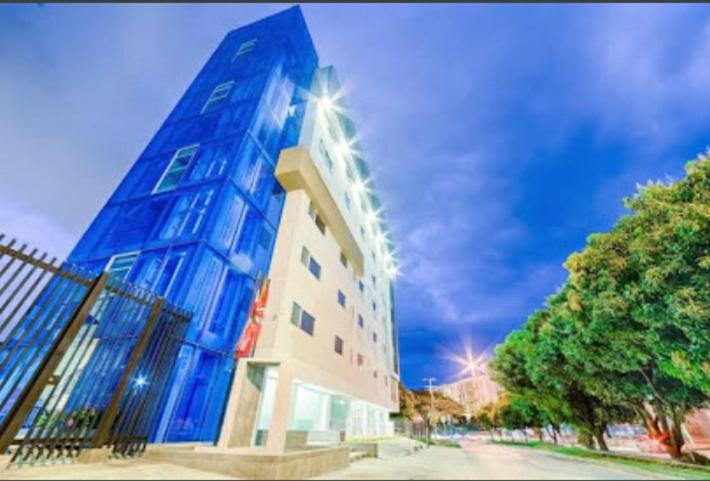 um edifício azul alto com uma árvore em frente em Hotel Blue 66 em Cali