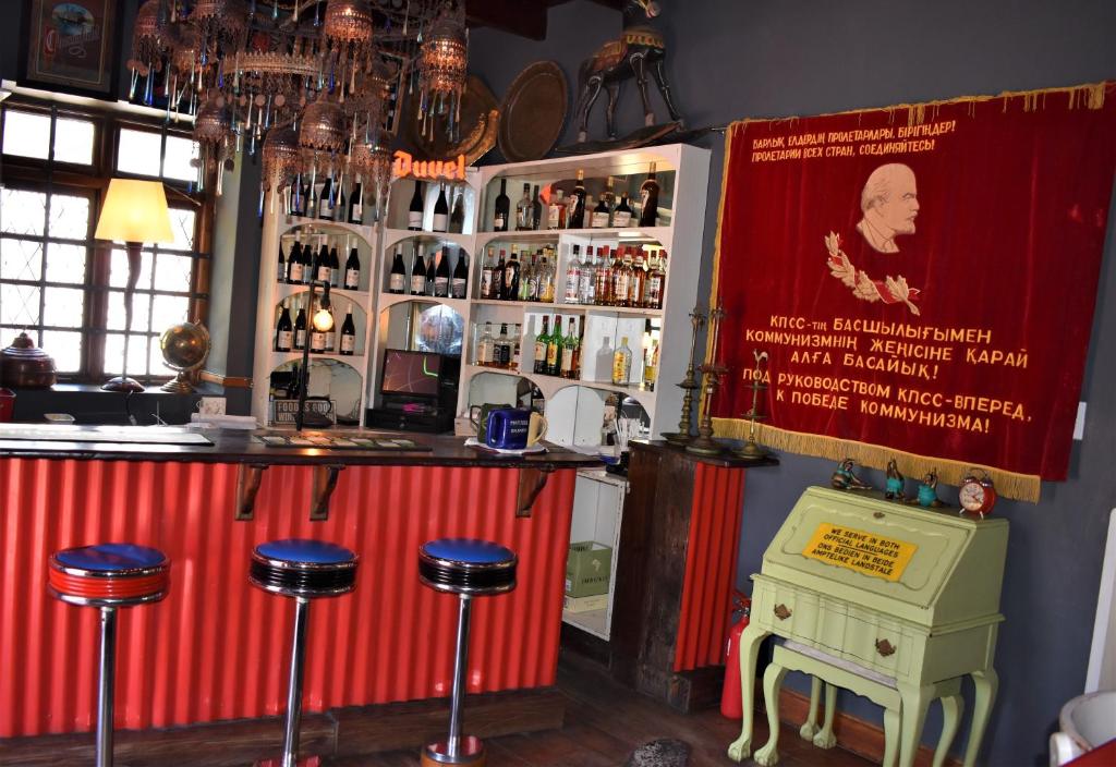 a bar with stools in front of a counter with wine bottles at Red Tin Roof in Riebeek-Kasteel