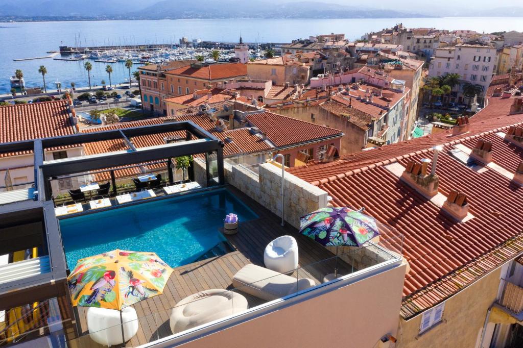 a swimming pool on the roof of a building with umbrellas at Hôtel Fesch & Spa in Ajaccio