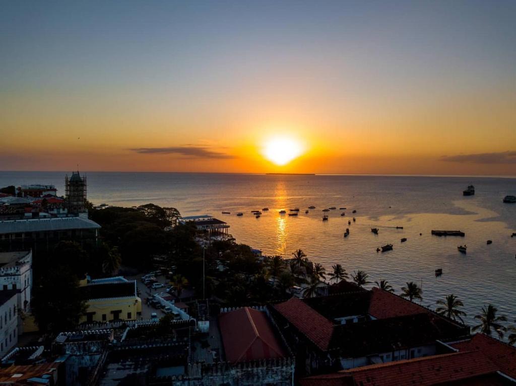 a sunset over the ocean with boats in the water at Stonetown View Inn in Zanzibar City