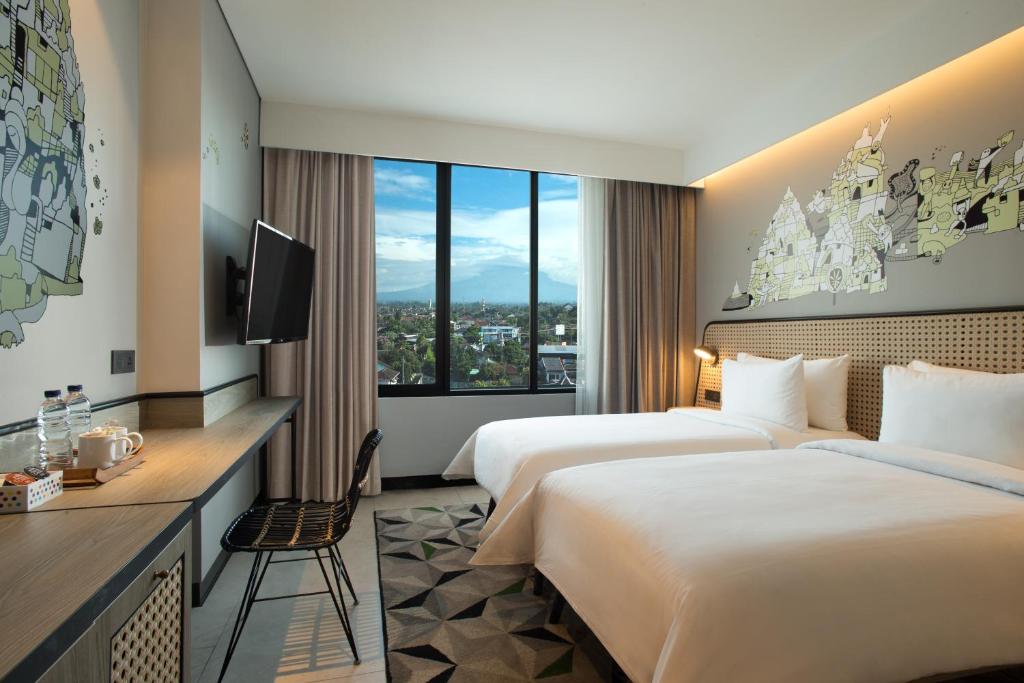 a hotel room with two beds and a television at ARTOTEL Yogyakarta in Yogyakarta