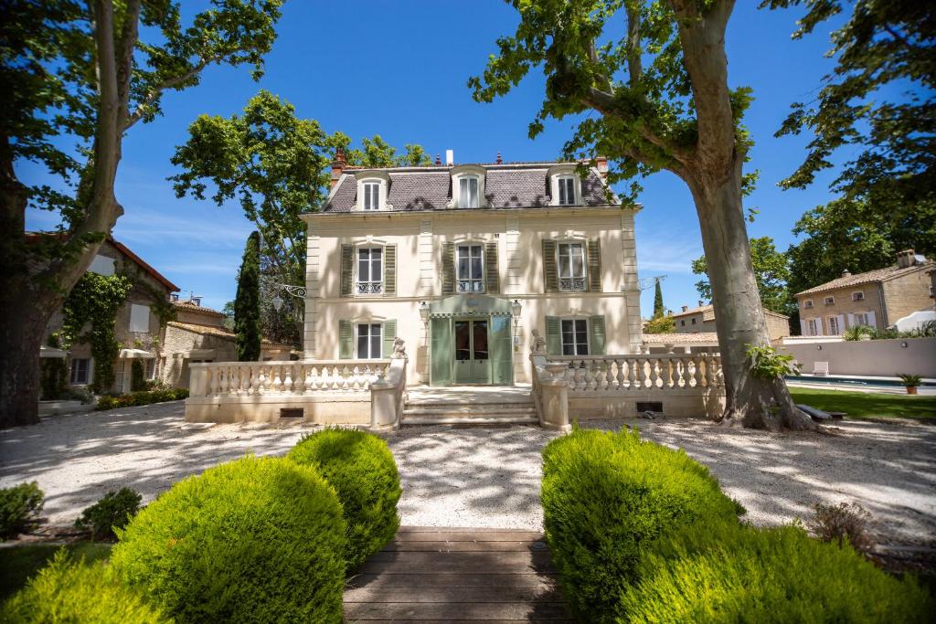 an exterior view of a large white house with trees at LES FRENES EN PROVENCE-CHÂTEAU ZEN in Avignon