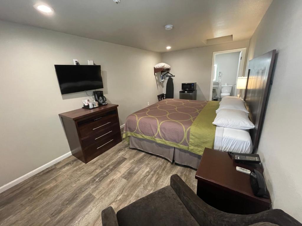 Cette chambre comprend un lit et une télévision à écran plat. dans l'établissement Budget Lodge Eugene - Airport, à Eugene