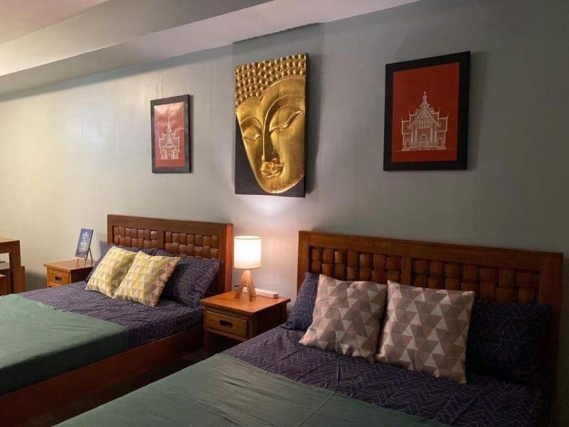 a bedroom with two beds and a gold head on the wall at Wind and Sea at Wind Residences in Tagaytay