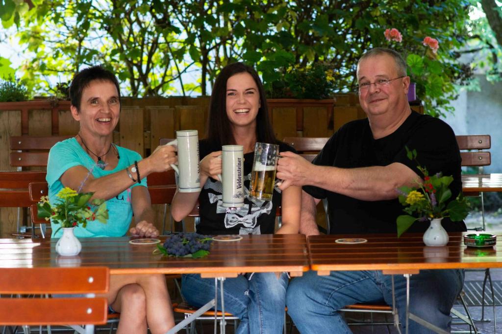 tres personas sentadas en una mesa bebiendo cerveza en Landgasthof Zum Elsabauern, en Königstein in der Oberpfalz