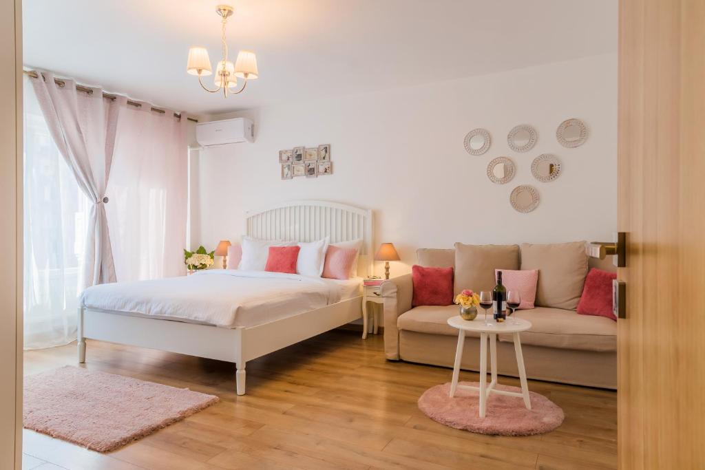 una camera bianca con un letto e un divano di Studio T by MRG Apartments a Bucarest