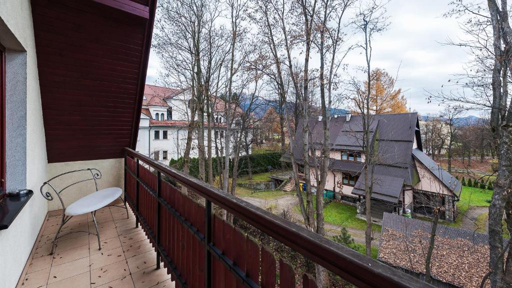 a balcony with a chair and a view of a house at Apartamenty Sun & Snow Centrum in Zakopane