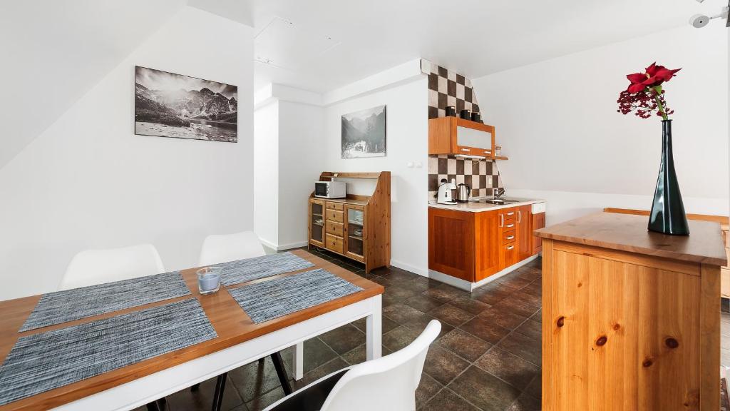 a kitchen with white walls and a table and chairs at Apartamenty Sun & Snow Centrum in Zakopane