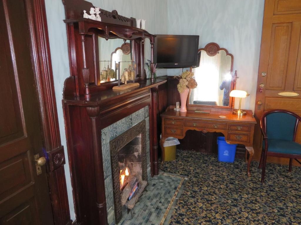 a living room with a fireplace with a tv and a mirror at Market Street Inn in Taylorville