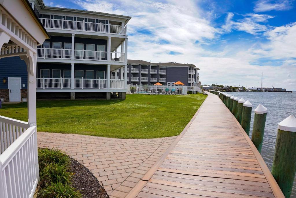 Comfort Suites Chincoteague Island Bayfront Resort في تشينكوتيج: مبنى به ممشى بجانب تجمع المياه