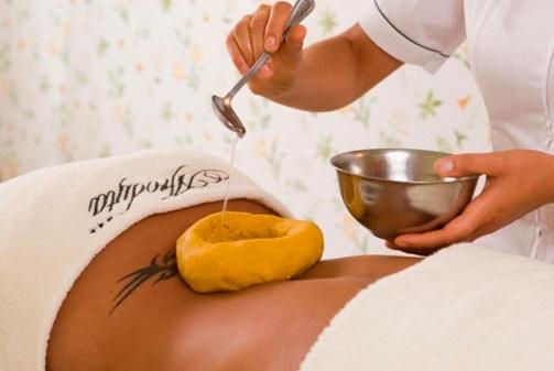 Spa treatment with warm oil being poured onto a person's back.