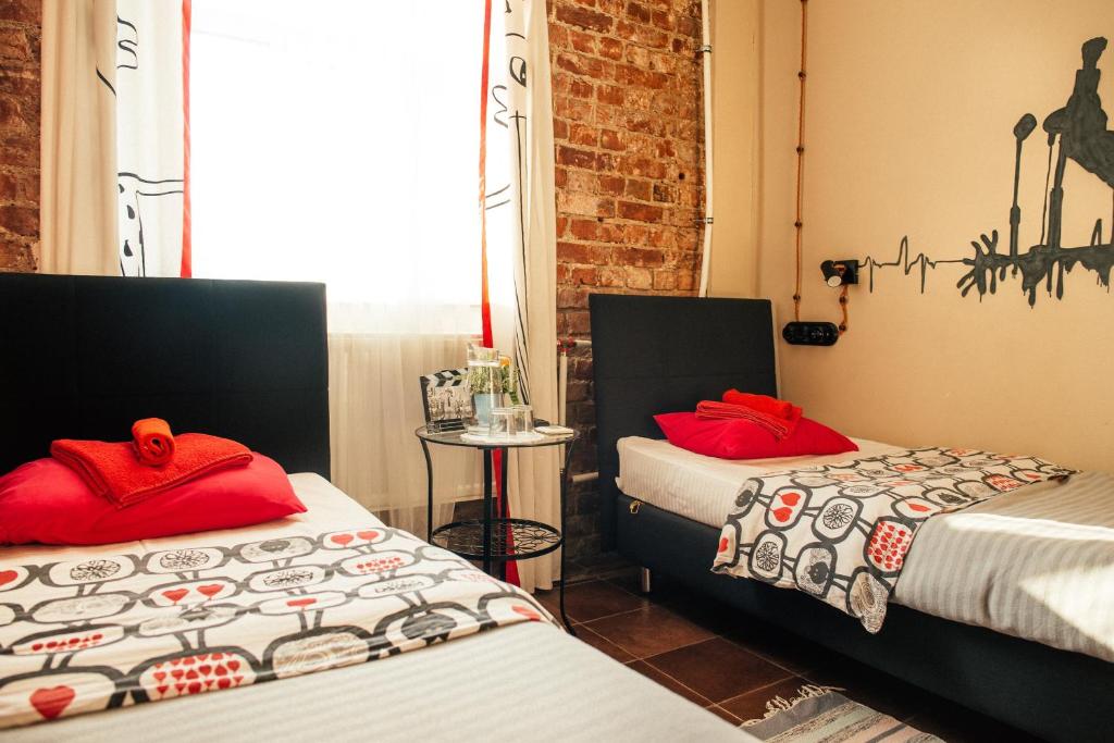 a room with two beds with red pillows at Kino Hostel on Vyborgskaya in Saint Petersburg