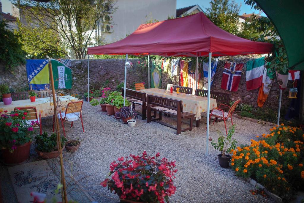 uma mesa de piquenique sob um guarda-sol vermelho num jardim em Majdas em Mostar