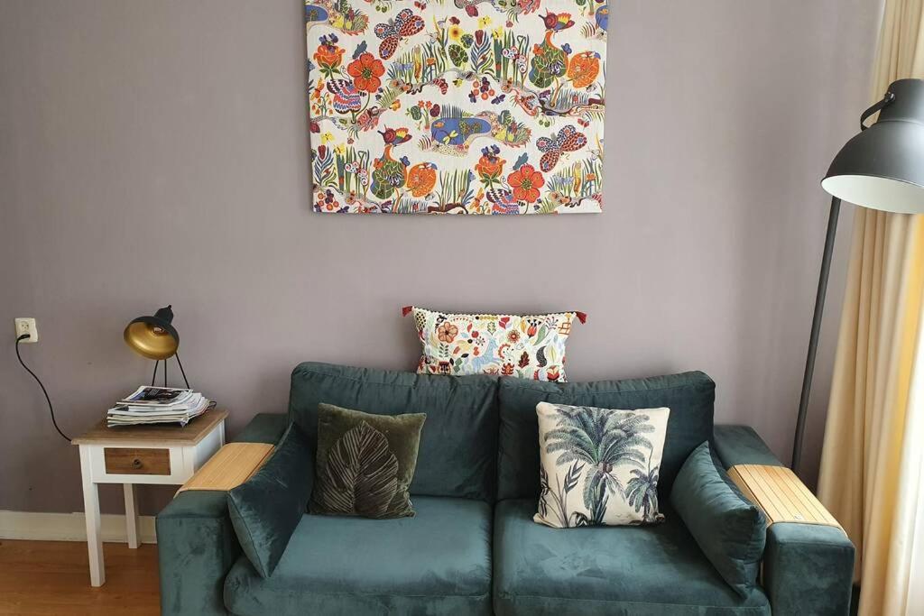 a green couch in a living room with a painting on the wall at Charming apartment in city center in Amsterdam