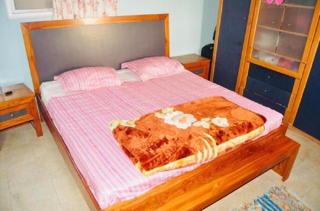 um quarto com uma cama com um cobertor rosa em CHAMBRES CLIMATISÉES EN VILLE em Saint-Louis